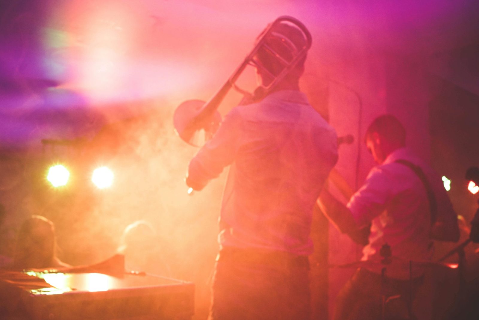 Vibrant live music performance featuring a trombone player on stage in a nightclub setting.